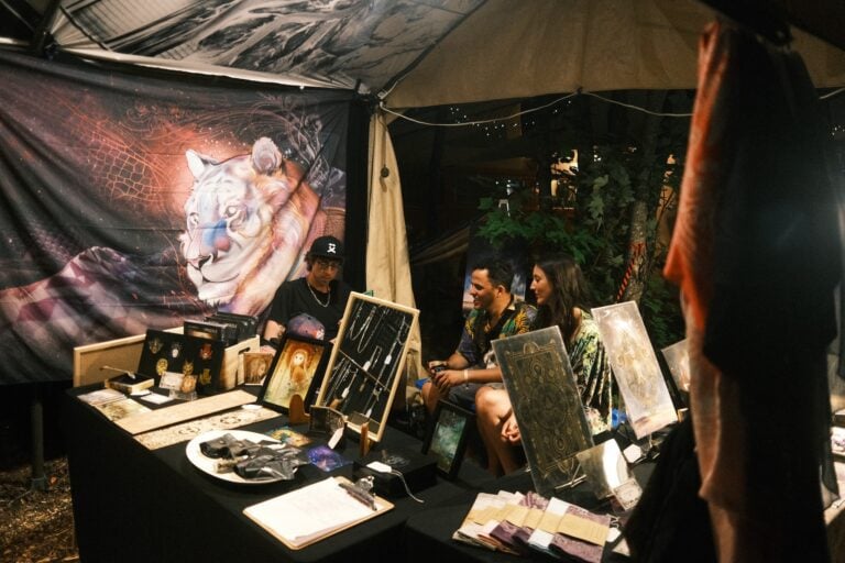 Kiosque d'art la nuit avec une tapisserie de félin, des œuvres encadrées et un présentoir à bijoux