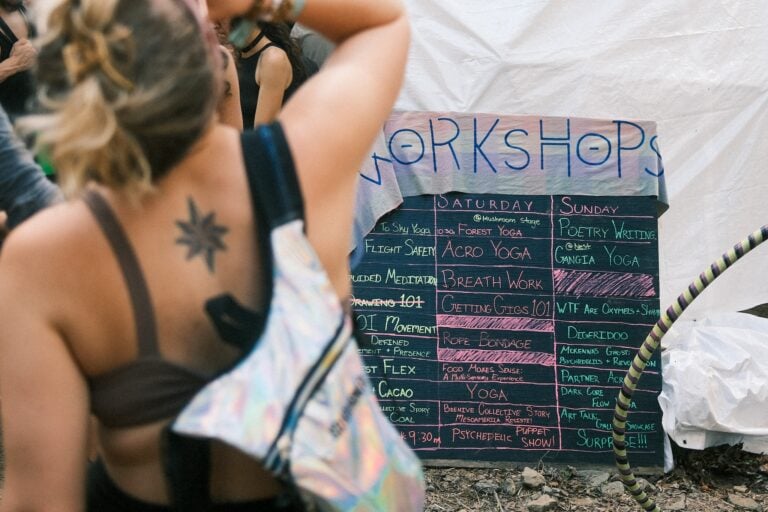 Tableau noir écrit à la main annonçant les ateliers du samedi et du dimanche, dont l'acroyoga et la respiration