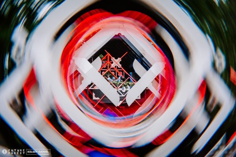 Flou tourbillonnant encadrant une scène blanche en losange à treillis rouge, au cœur d'un tunnel d'anneaux rouges et blancs
