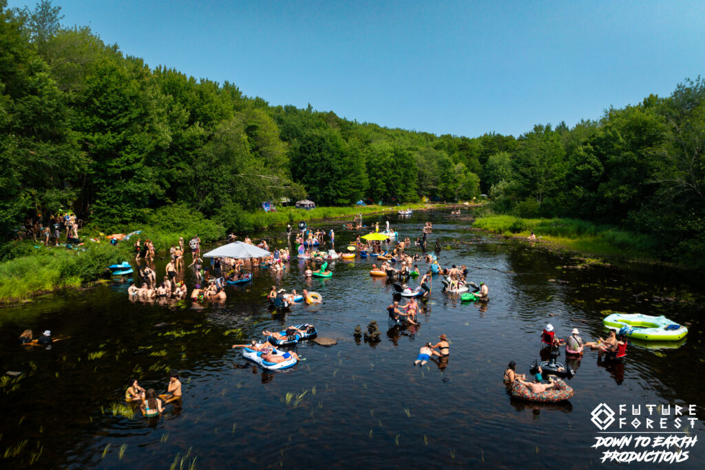 Festival-goers floating and cooling off in Little River at Future Forest
